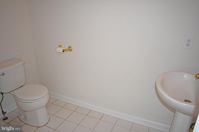 half bathroom featuring tile patterned floors, baseboards, a sink, and toilet