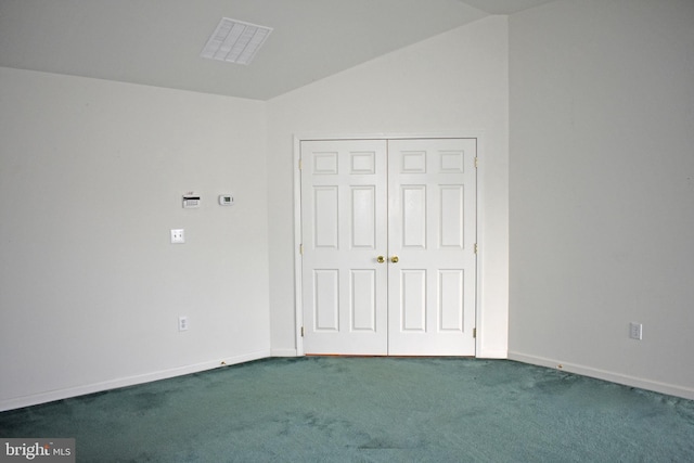 unfurnished bedroom with carpet, a closet, lofted ceiling, and baseboards
