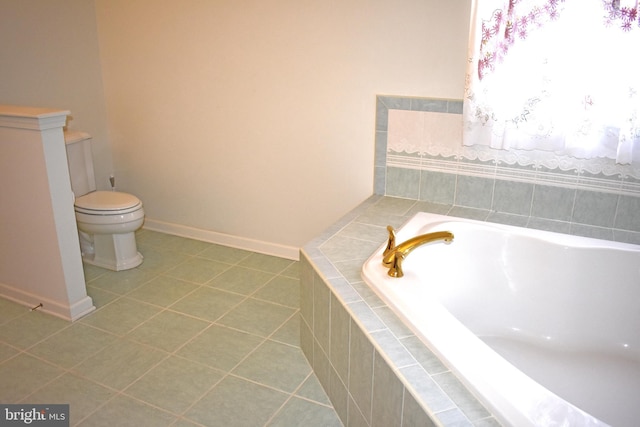 bathroom featuring tile patterned flooring, a bath, toilet, and baseboards