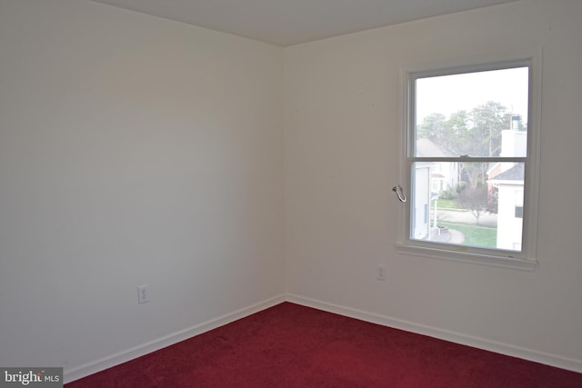 empty room featuring dark carpet, a healthy amount of sunlight, and baseboards