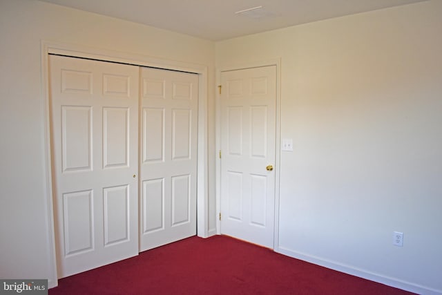 unfurnished bedroom featuring dark colored carpet and a closet