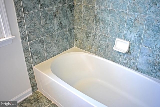 bathroom featuring a washtub and baseboards