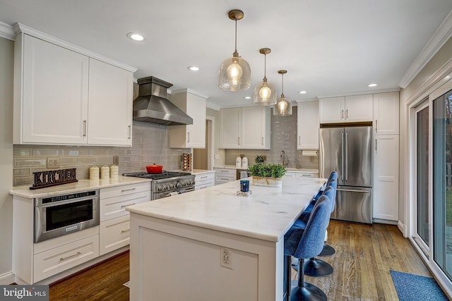 kitchen featuring wall chimney exhaust hood, premium appliances, dark wood-style flooring, and white cabinetry