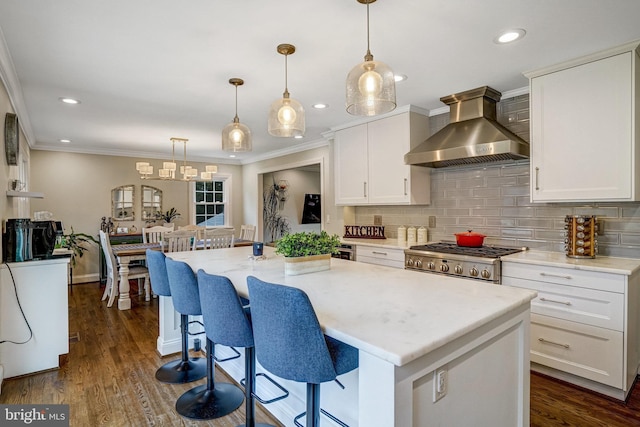 kitchen featuring wall chimney exhaust hood, tasteful backsplash, range, and white cabinetry