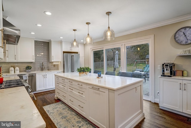 kitchen with high end refrigerator, dark wood finished floors, crown molding, wall chimney range hood, and a sink