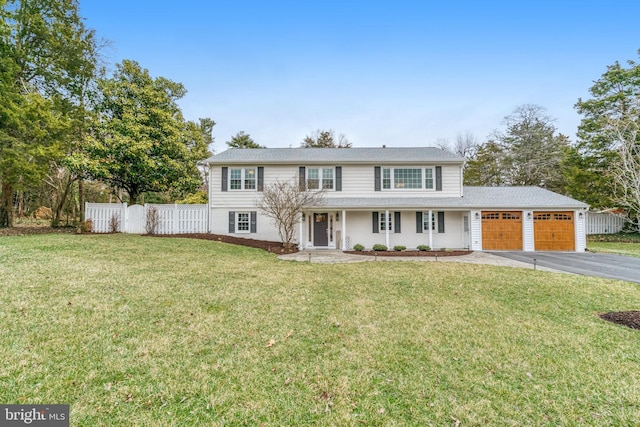 view of front of house featuring driveway, a front lawn, an attached garage, and fence