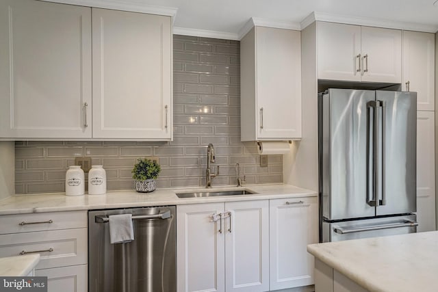 kitchen with stainless steel appliances, a sink, white cabinetry, decorative backsplash, and crown molding