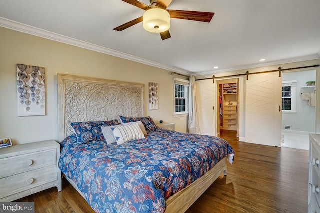 bedroom with a barn door, crown molding, ceiling fan, and wood finished floors