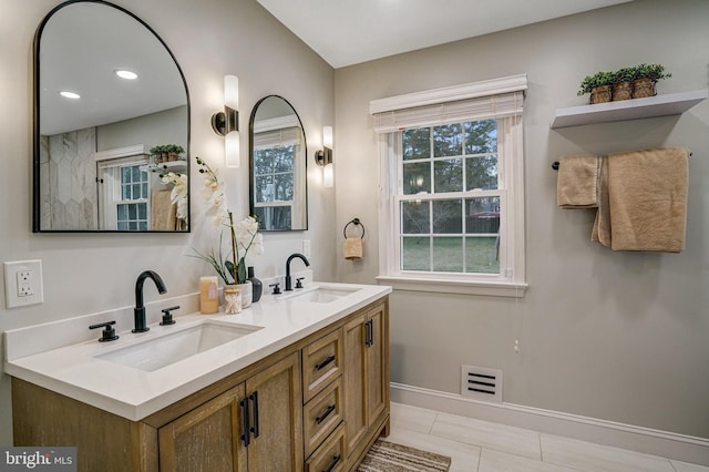 full bath with visible vents, a sink, baseboards, and double vanity