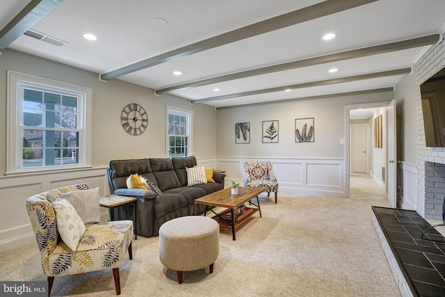 living room with visible vents, light colored carpet, beamed ceiling, a fireplace, and a decorative wall