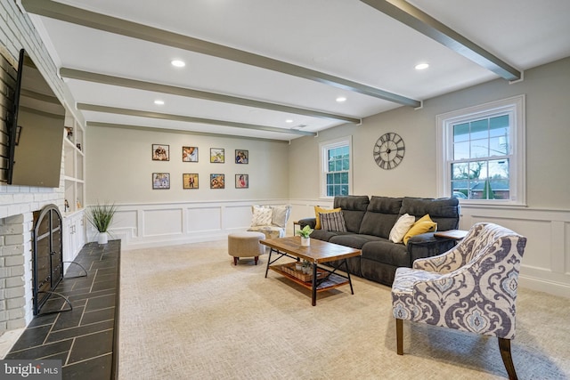 living room with beam ceiling, a fireplace, recessed lighting, a decorative wall, and wainscoting