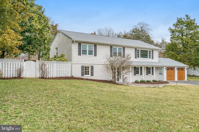 view of front of house with aphalt driveway, an attached garage, fence, a front yard, and brick siding