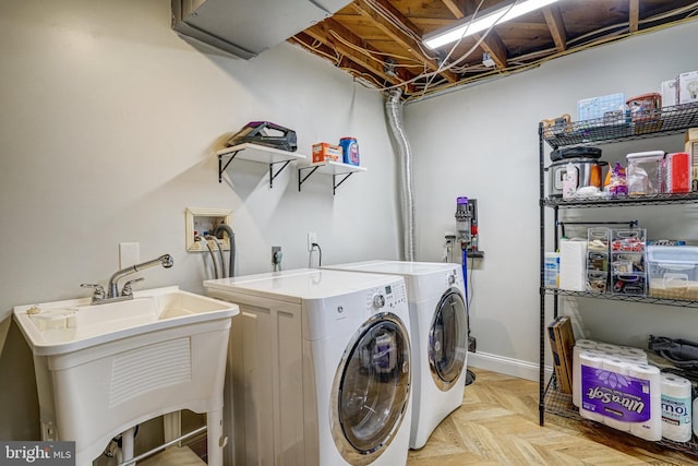 clothes washing area with laundry area, baseboards, a sink, and washing machine and clothes dryer