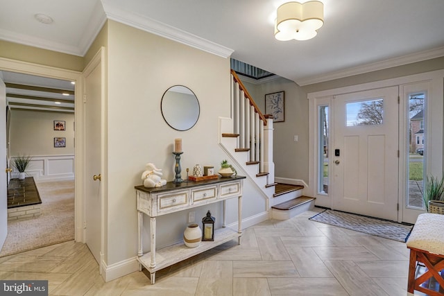 foyer entrance featuring stairway, baseboards, ornamental molding, and a decorative wall