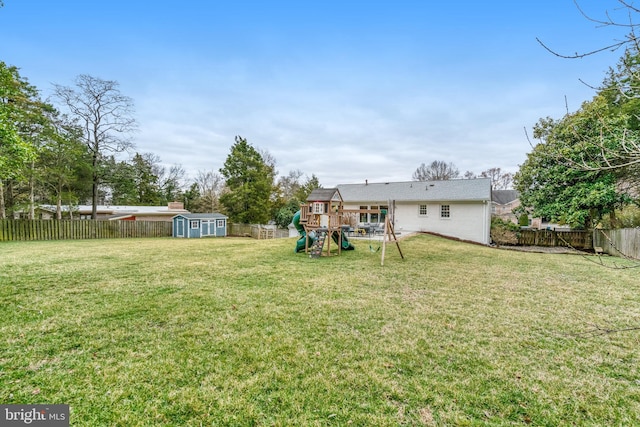 view of yard featuring a shed, a fenced backyard, a playground, and an outdoor structure