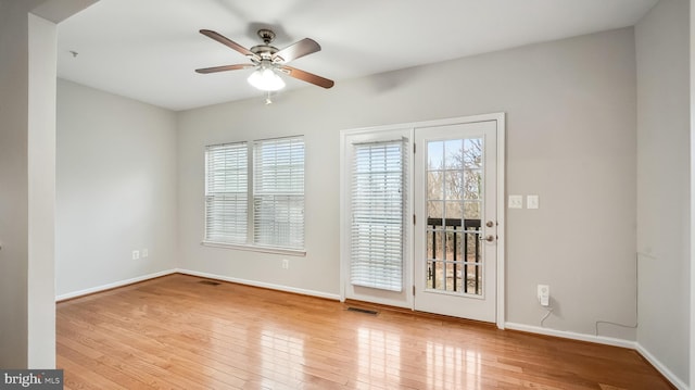 spare room featuring wood-type flooring, visible vents, ceiling fan, and baseboards