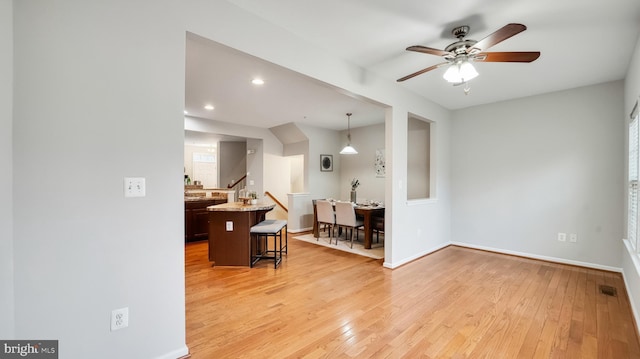 interior space with visible vents, stairway, light wood-style flooring, a ceiling fan, and baseboards