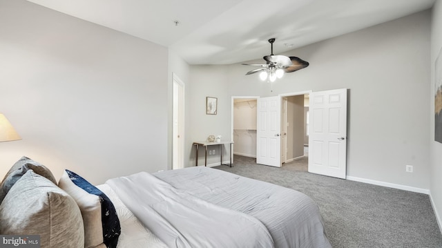 bedroom featuring a walk in closet, a closet, carpet flooring, ceiling fan, and baseboards