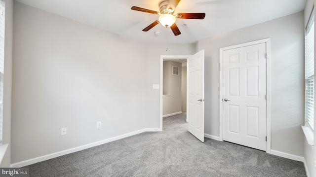 unfurnished bedroom featuring carpet flooring, ceiling fan, visible vents, and baseboards