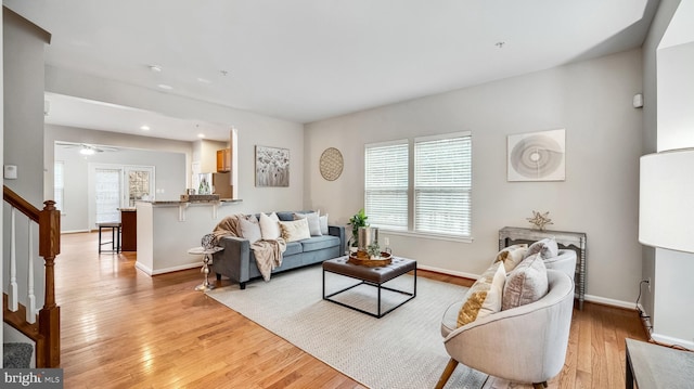 living room with light wood-style flooring, stairway, and baseboards