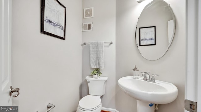 bathroom with toilet, a sink, and visible vents