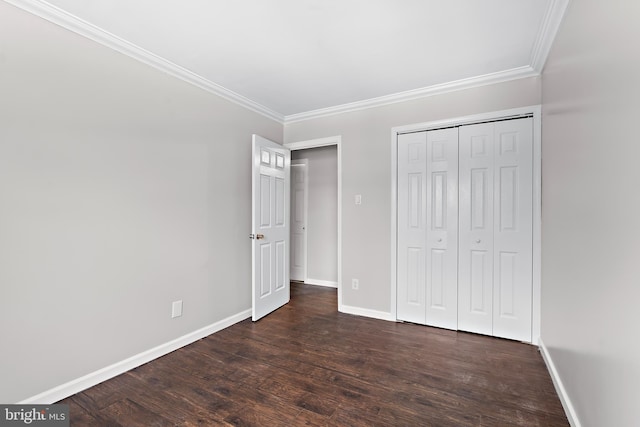 unfurnished bedroom featuring baseboards, a closet, dark wood finished floors, and crown molding