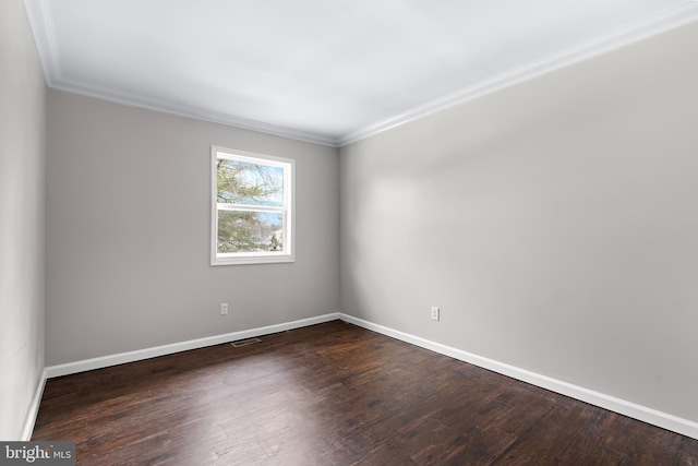 spare room with dark wood-type flooring, visible vents, and baseboards