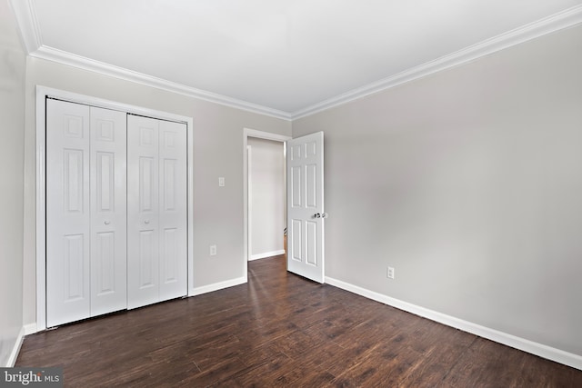 unfurnished bedroom featuring a closet, baseboards, dark wood-type flooring, and ornamental molding