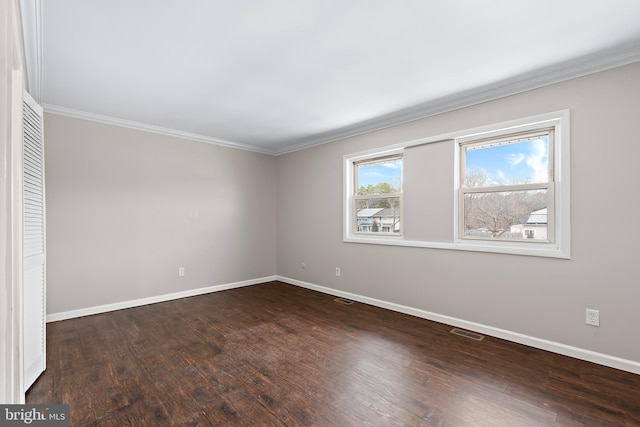 spare room featuring baseboards, crown molding, visible vents, and wood finished floors