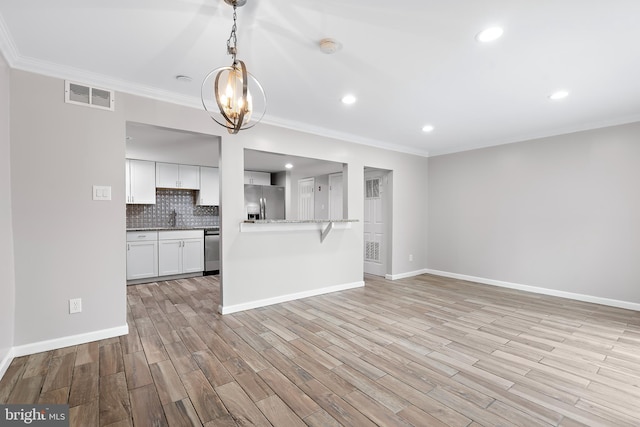 unfurnished living room with ornamental molding, light wood-style flooring, visible vents, and baseboards