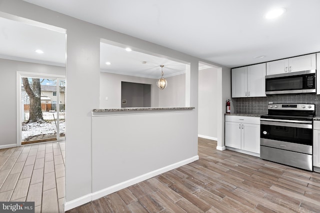 kitchen featuring light wood finished floors, tasteful backsplash, appliances with stainless steel finishes, ornamental molding, and white cabinetry