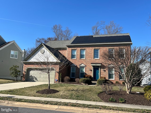 view of front of house featuring a front lawn, concrete driveway, an attached garage, brick siding, and solar panels