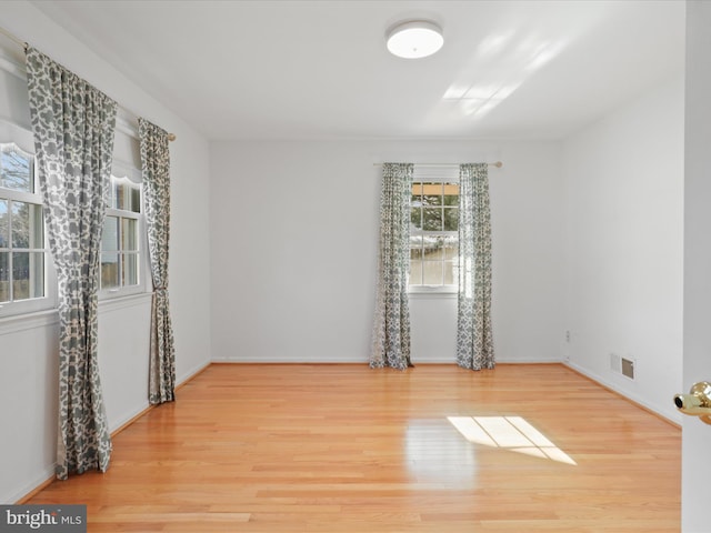 spare room with baseboards, visible vents, and wood finished floors