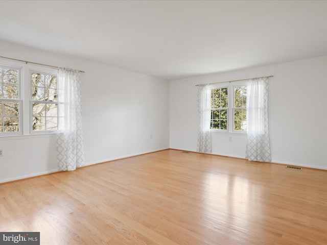 unfurnished room featuring visible vents, baseboards, and wood finished floors