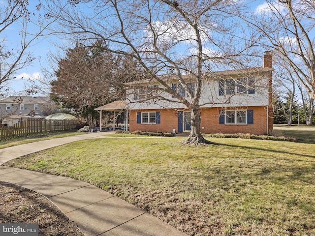 colonial inspired home featuring brick siding, a chimney, a front yard, fence, and driveway