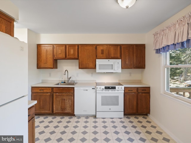 kitchen featuring white appliances, brown cabinets, light countertops, light floors, and a sink