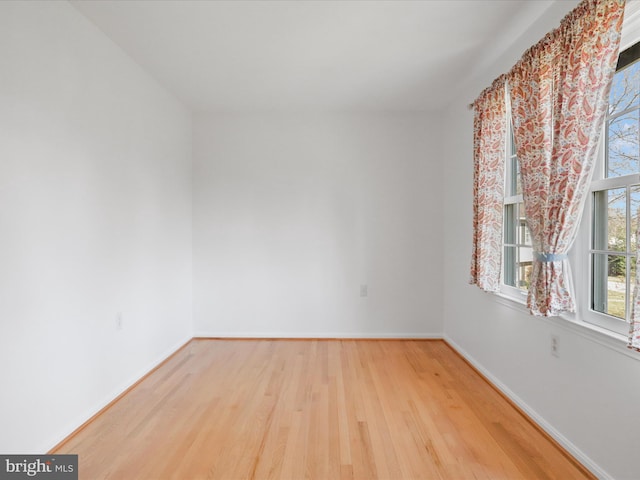 spare room with baseboards and wood finished floors