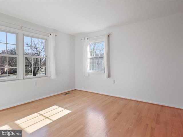 spare room featuring visible vents, baseboards, and wood finished floors