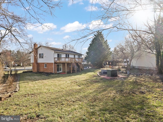 back of property with brick siding, a chimney, a lawn, stairway, and a deck