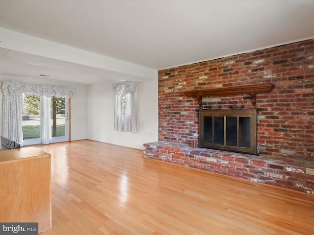 unfurnished living room featuring hardwood / wood-style flooring and a brick fireplace