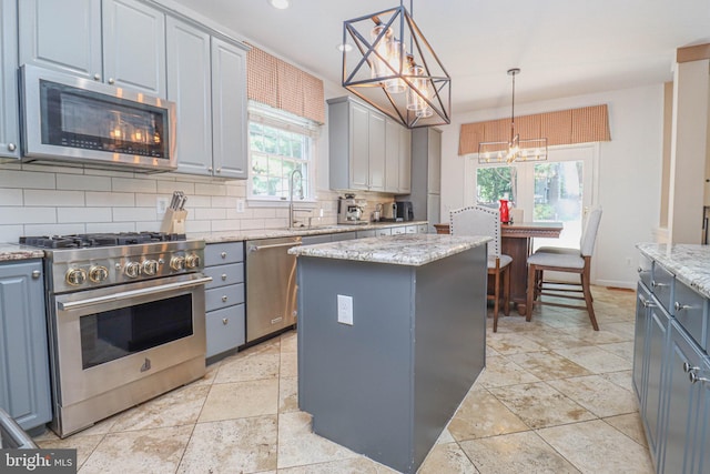 kitchen with appliances with stainless steel finishes, backsplash, gray cabinets, and a center island