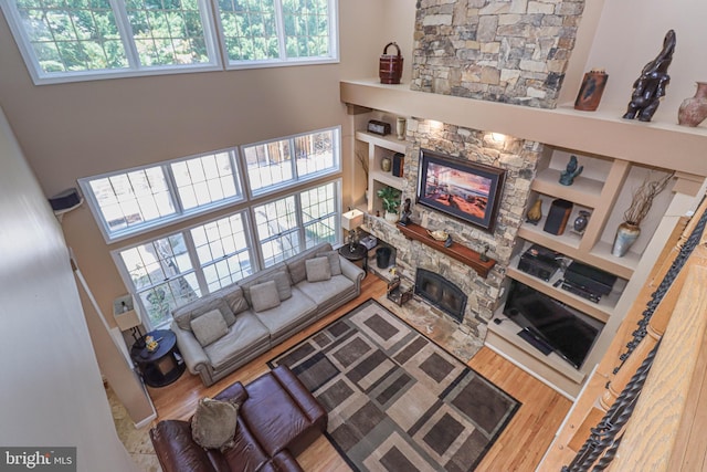 living room featuring a stone fireplace and wood finished floors