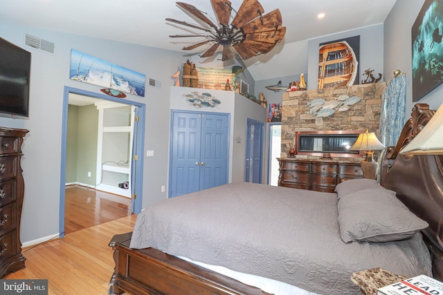 bedroom with vaulted ceiling, a closet, visible vents, and light wood-style floors