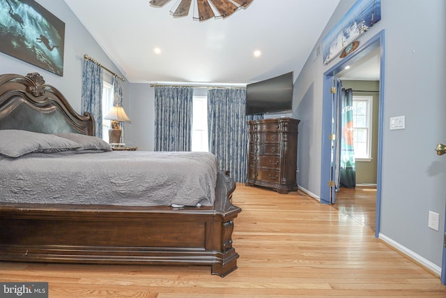bedroom with multiple windows, vaulted ceiling, baseboards, and wood finished floors