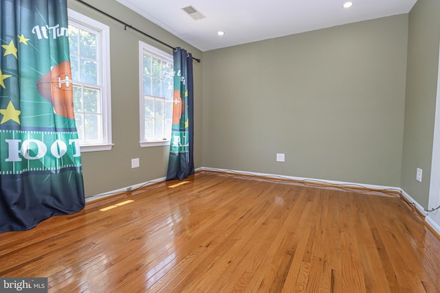 empty room with hardwood / wood-style flooring, recessed lighting, visible vents, and baseboards