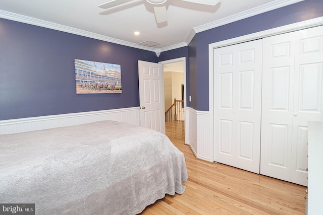 bedroom featuring visible vents, a wainscoted wall, wood finished floors, crown molding, and a closet