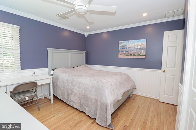 bedroom with a wainscoted wall, light wood finished floors, and crown molding