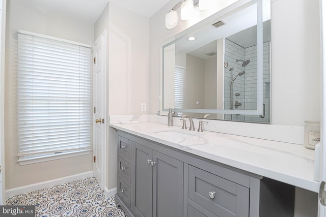 bathroom with baseboards, visible vents, tiled shower, tile patterned floors, and vanity