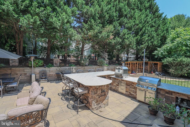 view of patio featuring a grill, outdoor dry bar, a fenced backyard, and area for grilling