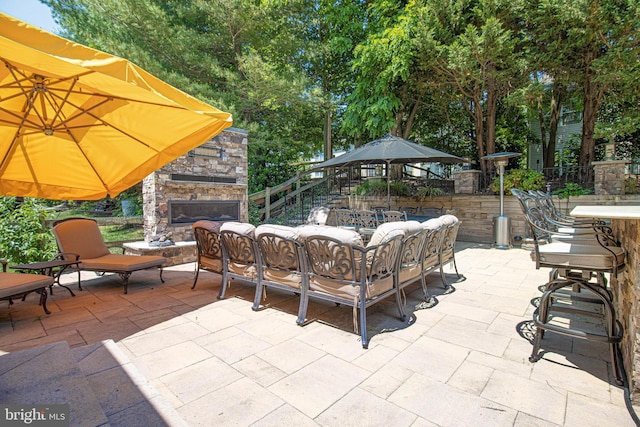 view of patio / terrace with an outdoor living space with a fireplace and fence